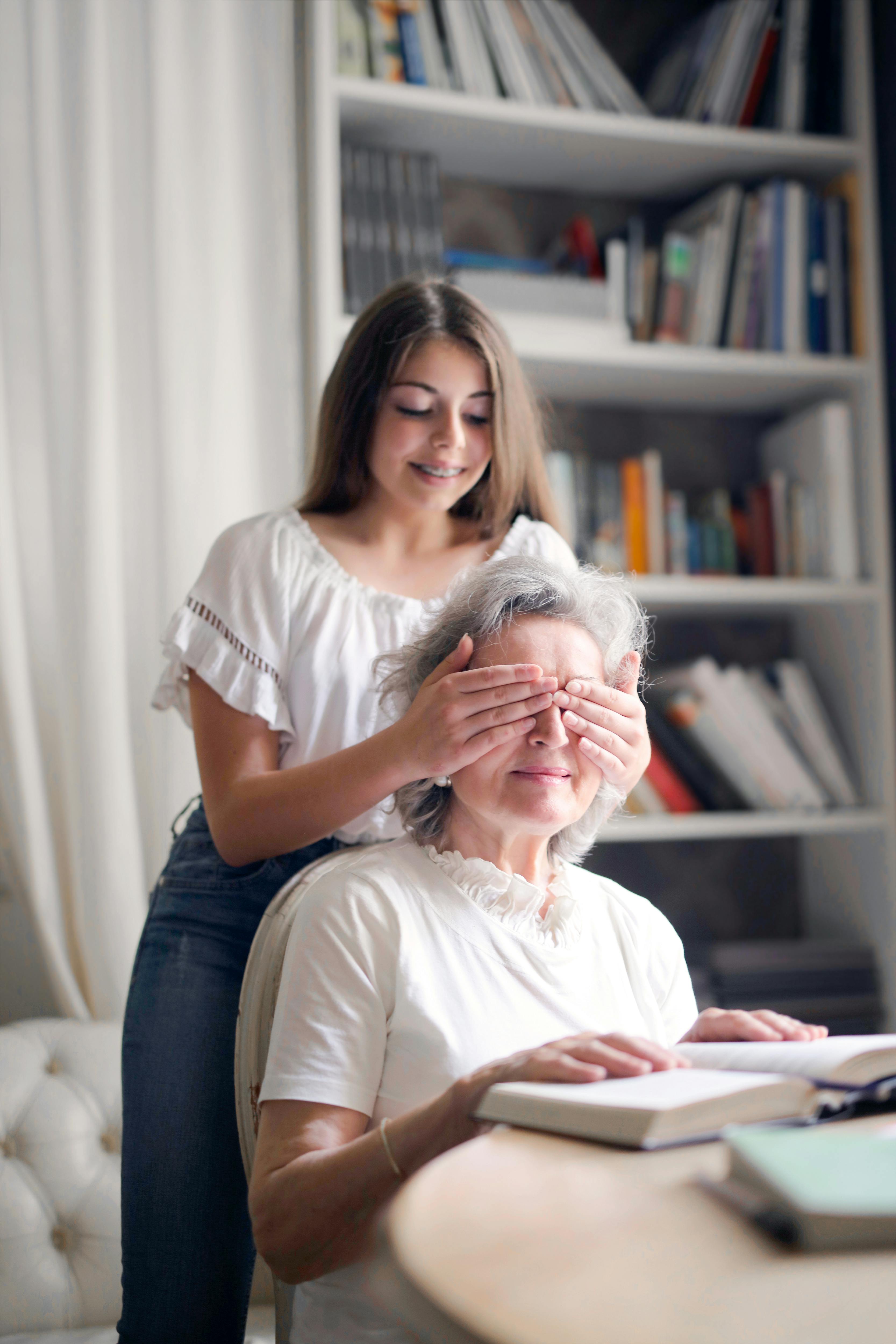 Ein Kind hält einer Seniorin die Augen zu